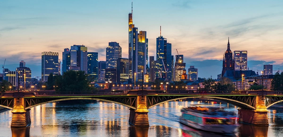 Skyline von Frankfurt am Main mit Mainbrücke und Ausflugsboot in der Abenddämmerung